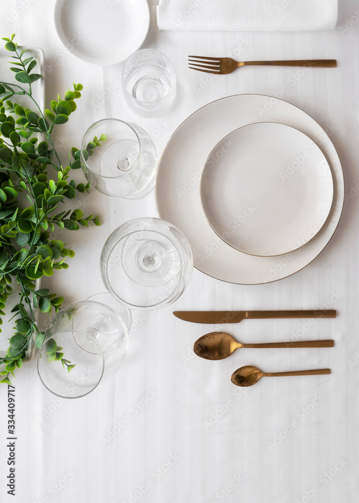Top view of tableware with linen napkins, gold cutlery and white porcelain plates. Minimalist table settings background for dinner. Top view of tableware with linen napkins, gold cutlery and white porcelain plates. Minimalist table settings background for dinner.