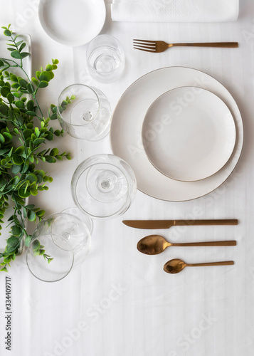 Top view of tableware with linen napkins, gold cutlery and white porcelain plates. Minimalist table settings background for dinner.