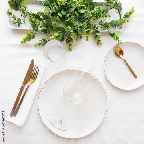 Top view of tableware with linen napkins, gold cutlery and white porcelain plates. Table settings background