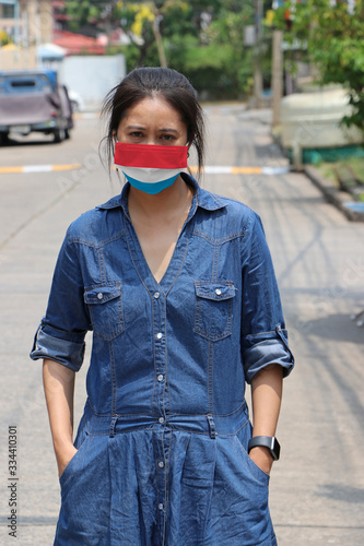 Luxembourg flag on hygienic mask. Masked woman prevent germs and wear denim skirt dress. Tiny Particle or virus corona or Covid 19 protection.