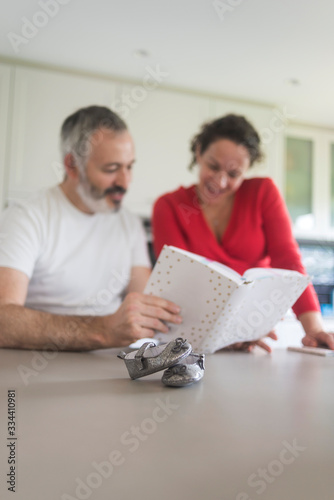 Happy pregnant woman with her husband sitting at home. Smiling couple consulting a book at the kitchen. © Rafa Fernandez