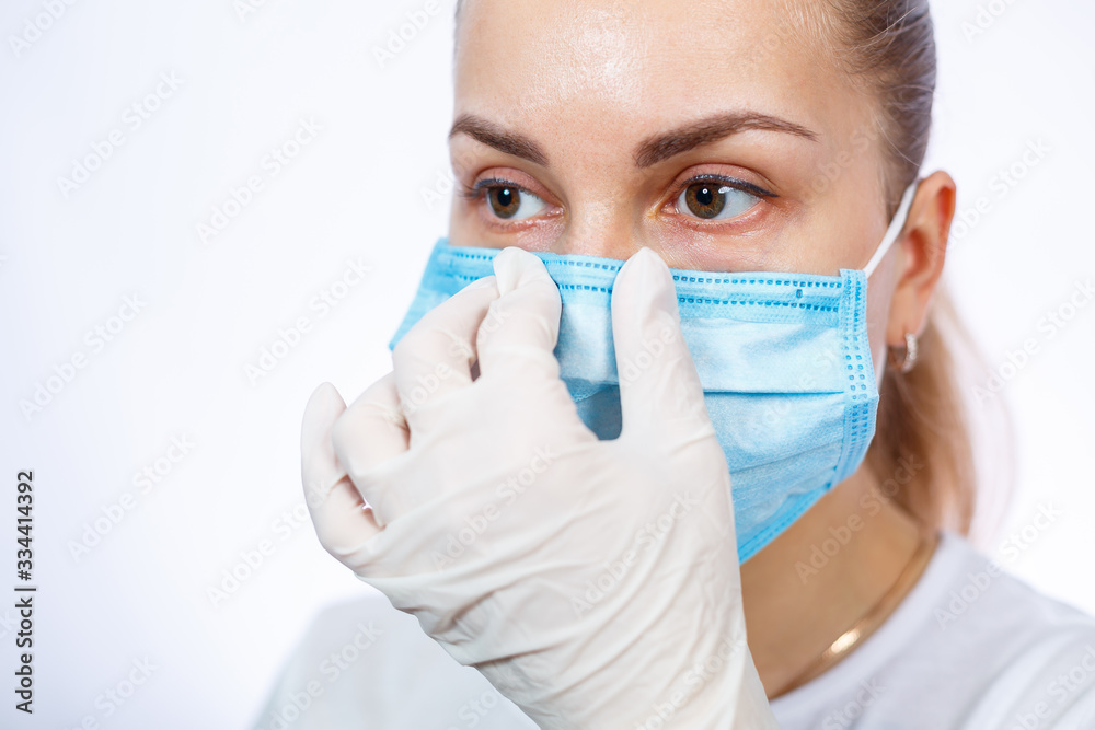 woman health worker demonstrates how to wear a protective medical surgical mask against the virus. Isolated on white background woman health worker demonstrates how to wear a protective medical surgical mask against the virus. Isolated on white background