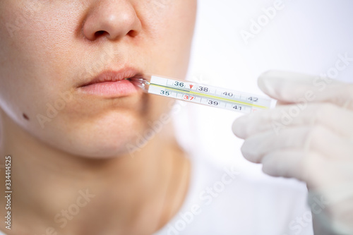 diseased woman in protective medical surgical mask with a thermometer in his hand treated against the virus. Isolated on white background