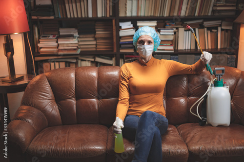 Woman with protective antiviral mask, chemical decontamination sprayer bottle in home isolation.