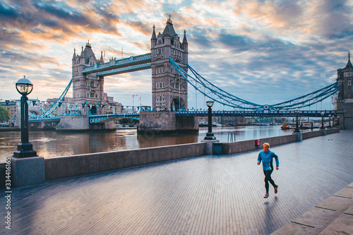 Alone runner in empty streets of london in Coronavirus, Covid-19 quarantine time. Tower Bridge in background