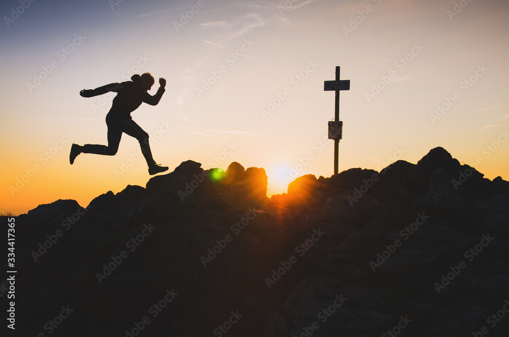 Silhouette of runner who run on the top of the hill during calm summer sunset - trail run in mountains, concept photo with copy space
