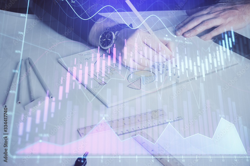 Double exposure of man's hands writing notes of stock market with forex chart.