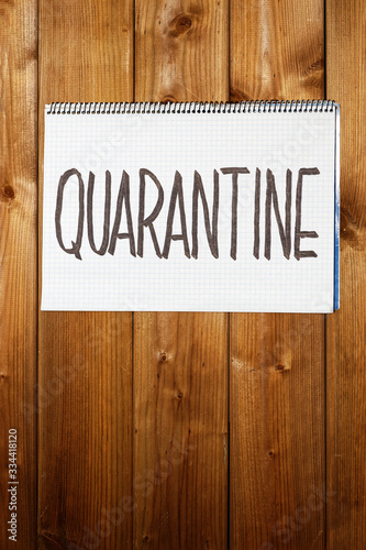 Closeup handwritten warning sign "Quarantine" on wooden wall or door. Concept warning about epidemiological quarantine.