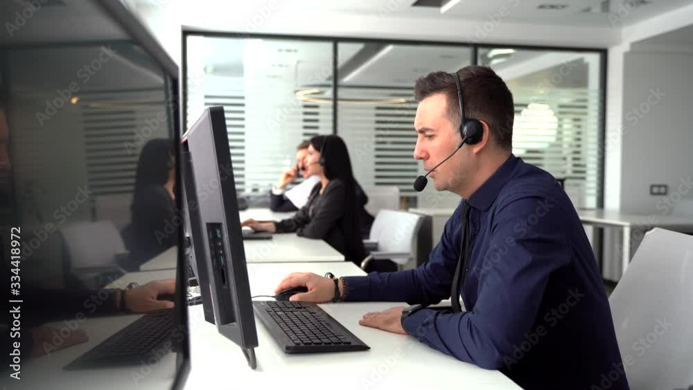 Handsome male customer service agent working in call center office as a telemarketer.