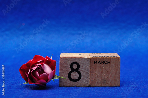 8 March on wooden blocks with a red rose on a blue background