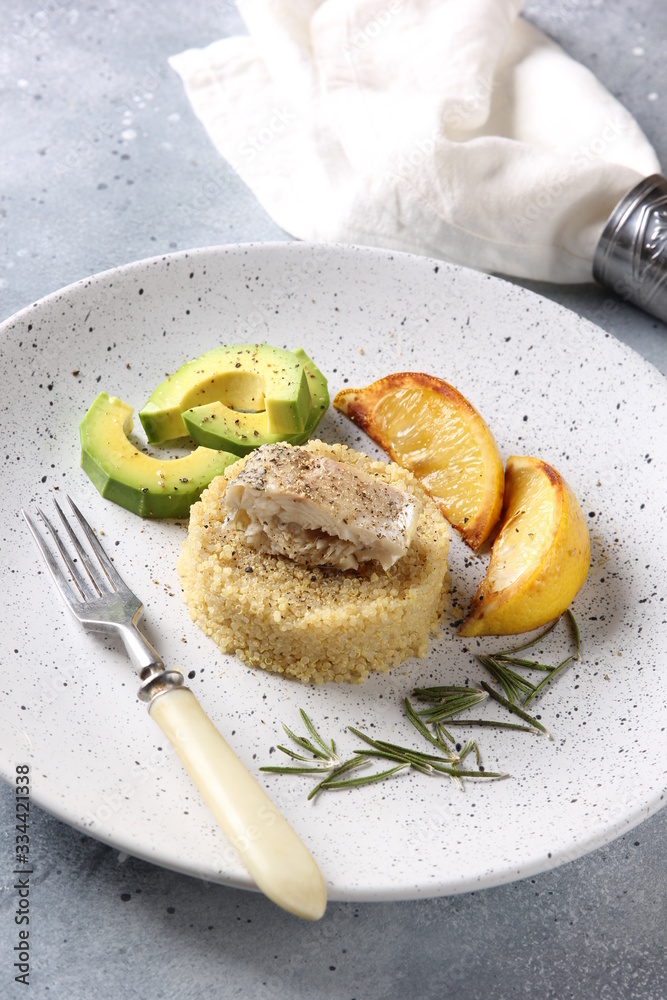 Healthy food. Quinoa with fish, avocado, lemon and rosemary on a light plate on a grey background. White napkin and fork. Background image, copy space Healthy food. Quinoa with fish, avocado, lemon and rosemary on a light plate on a grey background. White napkin and fork. Background image, copy space