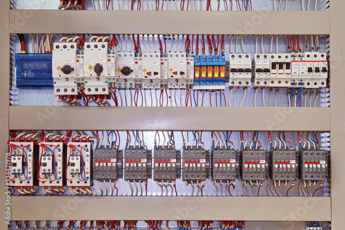 Electrical contactors or starters, motor protection circuit breakers, intermediate relays are arranged in several rows in the electrical Cabinet. Components are connected by electrical wires, cables.