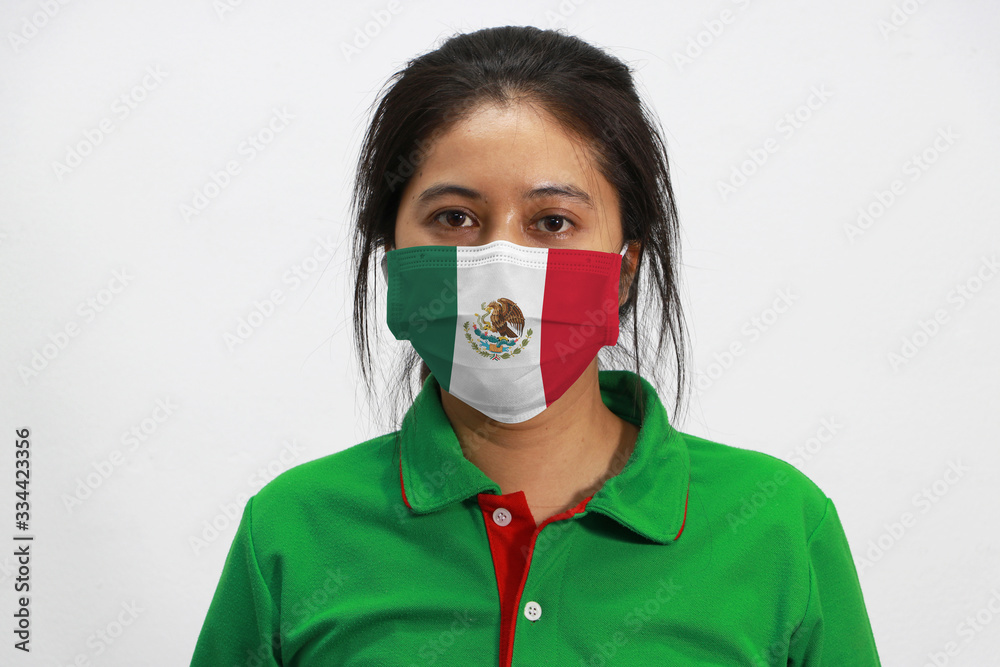 Mexico flag on hygienic mask. Masked woman prevent germs and wear green shirt. Tiny Particle or Covid-19 protection. Mexico flag on hygienic mask. Masked woman prevent germs and wear green shirt. Tiny Particle or Covid-19 protection.