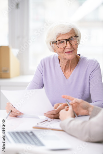 Pretty senior woman in eyeglasses and casualwear holding insurance document