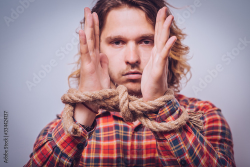 Tortured business man holding his hands tied with a rope