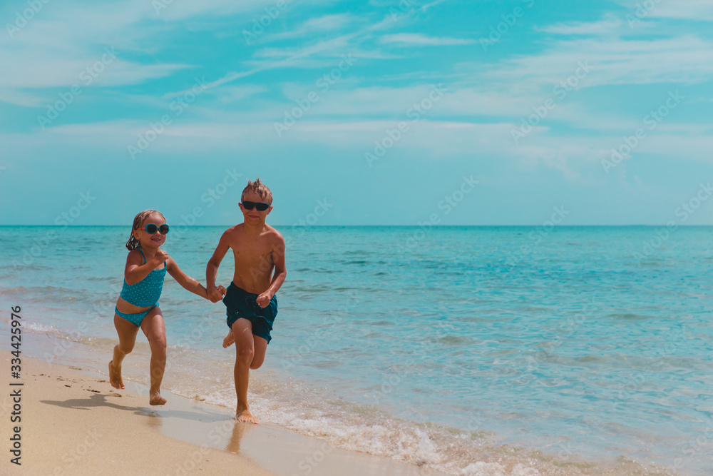 happy girl and boy run and play with water at beach