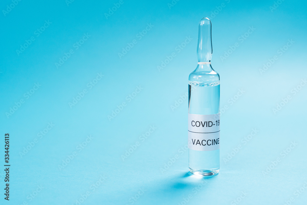 Coronavirus vaccine. Glass ampoule with a medicine for COVID-19 on a blue background. Copyspace. Close-up. Search and application of a new injection Coronavirus vaccine. Glass ampoule with a medicine for COVID-19 on a blue background. Copyspace. Close-up. Search and application of a new injection