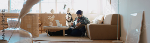 Obraz na plátne Middle Eastern male working from home, having a video call, dog sits near him