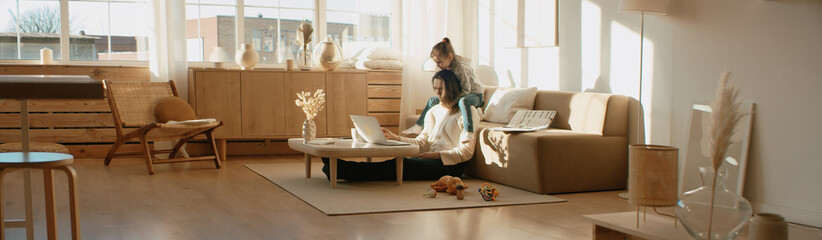 Mother working from home, having a phone call, while her daughter distracts her and drawing attention