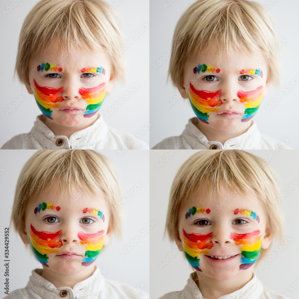 Beautiful blond toddler boy with rainbow painted on his face and messy hands Beautiful blond toddler boy with rainbow painted on his face and messy hands