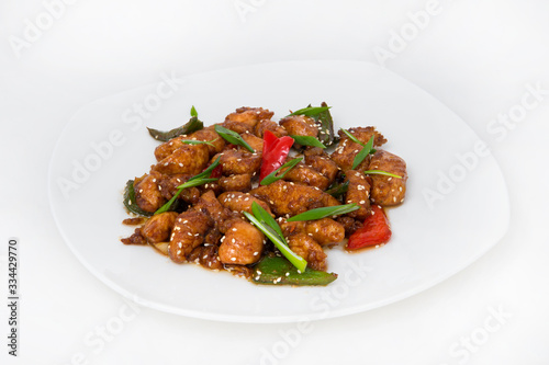 Braised chicken slices in a sauce with colored sweet pepper and slices of green onions for decoration