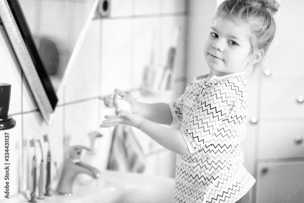 Cute little toddler girl washing hands with soap and water in bathroom. Adorable child learning cleaning body parts. Hygiene routine action during viral desease. kid at home or nursery. Cute little toddler girl washing hands with soap and water in bathroom. Adorable child learning cleaning body parts. Hygiene routine action during viral desease. kid at home or nursery.