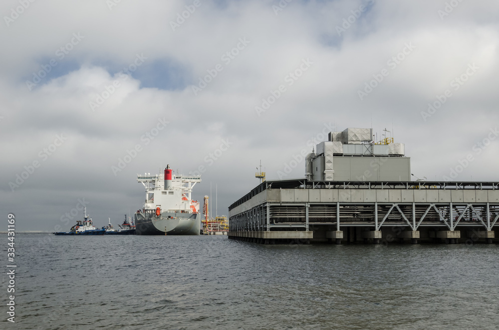 LNG TERMINAL AND GAS TANKER - A large ship maneuvers into the unloading quay