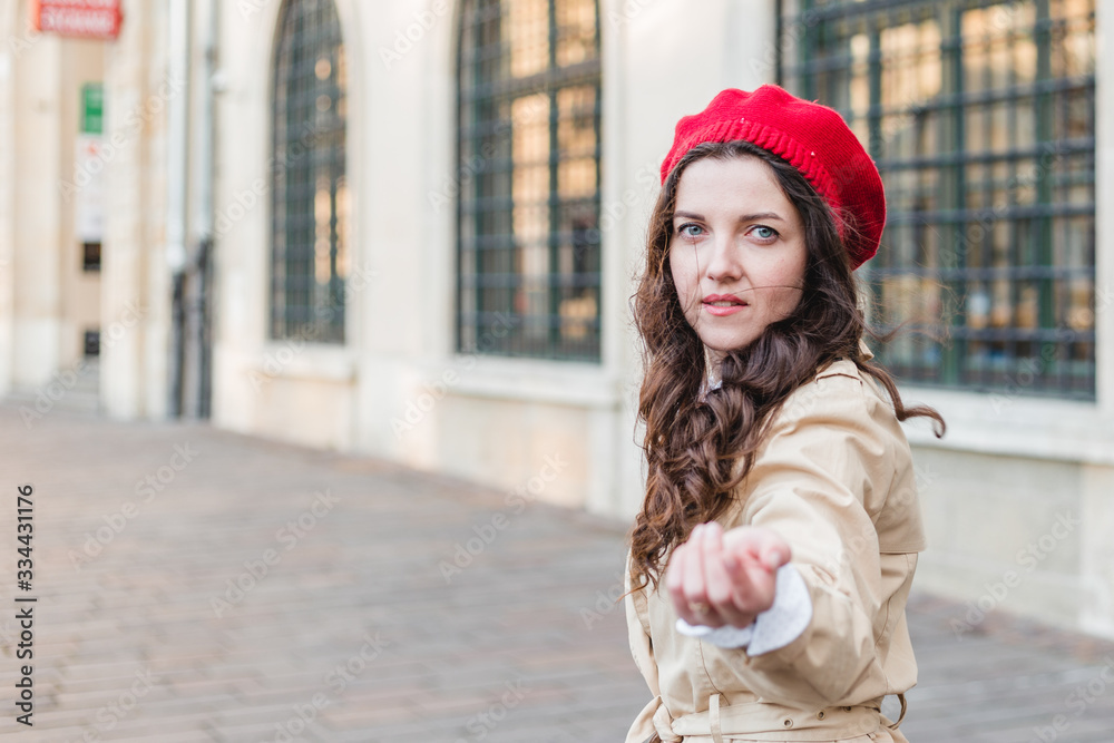 Obraz premium Beautiful young woman at city street. Happy tourist girl walking outdoors. Spring portrait of pretty brunette female posing in old town. Follow me to city