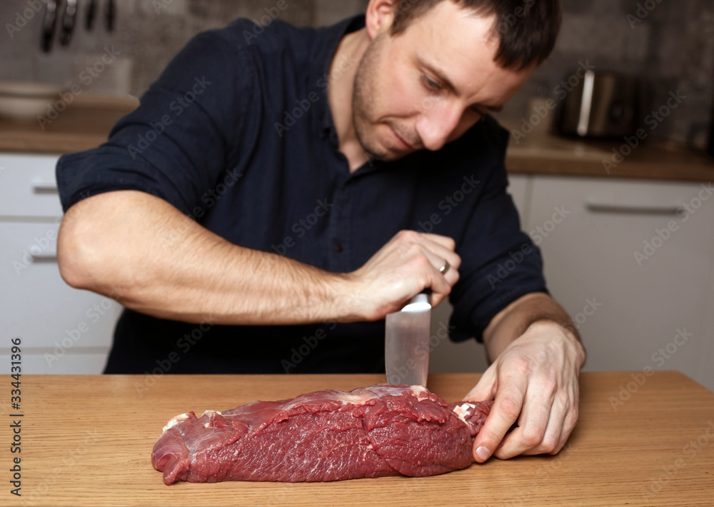 man cuts fresh meat with a knife