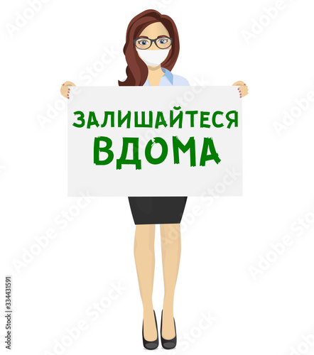 Woman with mask holds a white sheet with text stayhome (ukrainian language)