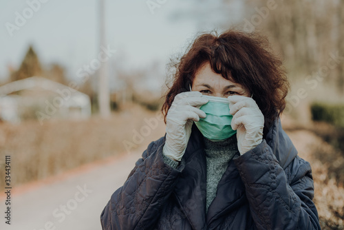 elderly woman wearing facial mask and gloves to prevention of infection