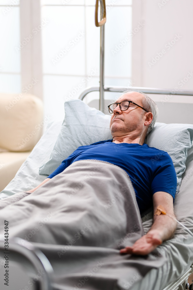 Retired old man in nursing home laying on bed