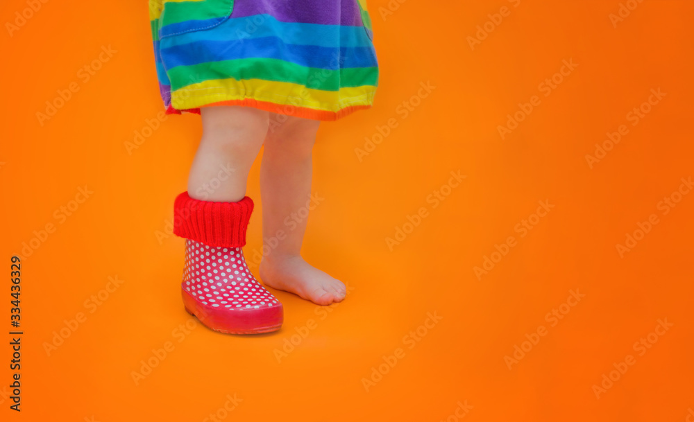 Children's foot in one rubber boot. One leg is bare barefoot. Baby