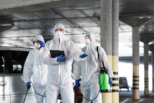 Virologists in protective suits on duty on public parking for first aid