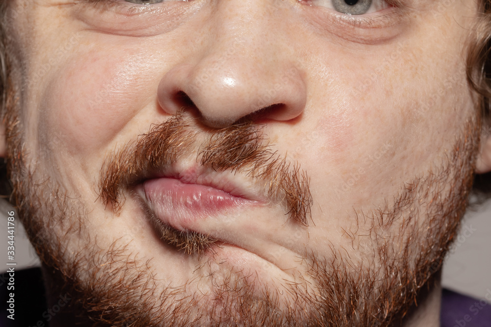 Uncertain. Close up of face of beautiful caucasian young man with redhair beard, focus on mouth. Human emotions, facial expression, cosmetology, body and skin care concept. Well kept skin. Wellbeing. Uncertain. Close up of face of beautiful caucasian young man with redhair beard, focus on mouth. Human emotions, facial expression, cosmetology, body and skin care concept. Well kept skin. Wellbeing.