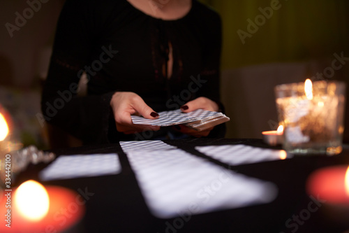 Wall Mural Close-up of fortuneteller's hands with cards at table with candles