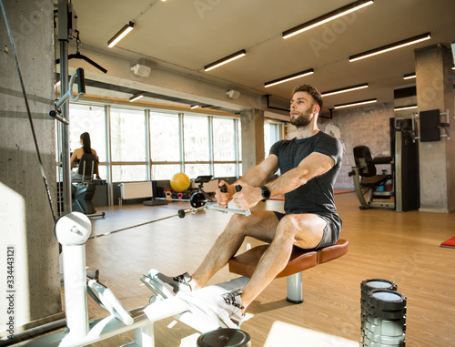 Young man using seated row ...
