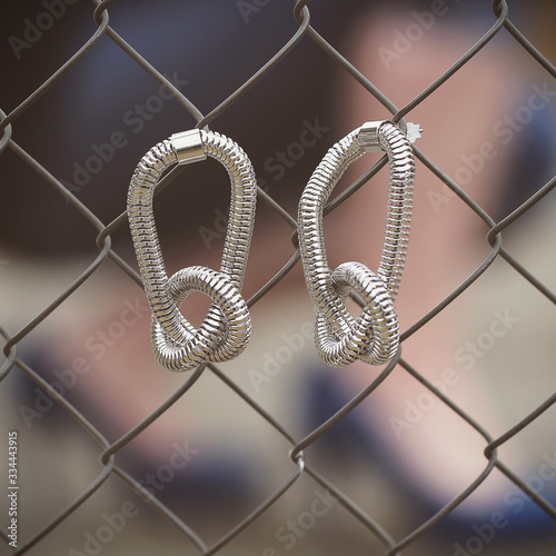 silver spring earrings hang on a grid next to women's feet photo