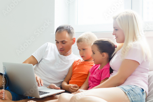 Beautiful smiling multiethic family in front of the laptop video call with distant parents at home. © Angelov