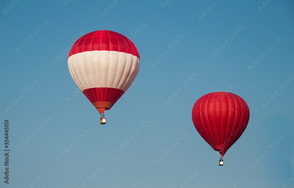 Naklejka premium Colorful hot-air balloons fly in the blue sky. red balloon. red and white balloons. Space for text.