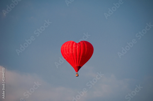 Colorful hot-air balloon in shape of heart on blue sky background. Red balloon. Holidays card with copy space. Valentines day background. Space for text.