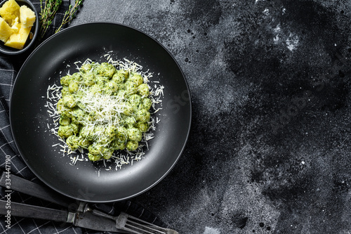 Potato gnocchi  with pesto, parmesan  cheese and spinach. Italian pasta. Black background. Top view. Copy space photo