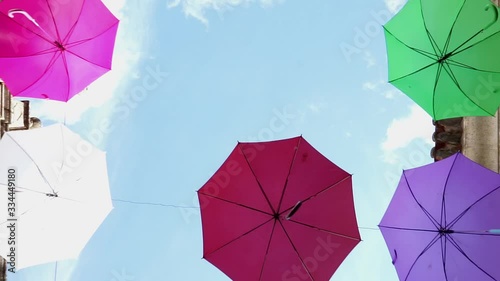 Walking down the street with colorful umbrellas hanged between the buildings of a street in Portugal.