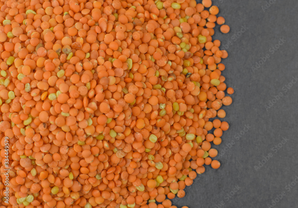 Stack of orange lentil seeds gathered together before a dark gray background