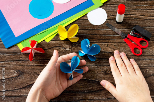 Child holds a paper butterfly decor or summer garland. Handmade paper ideas. The project of children's creativity, crafts, crafts for children.