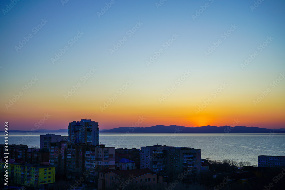 Sunset on the background of the sea and urban landscape,
