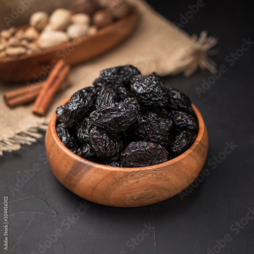 dried fruit in a square wooden bowl on a dark background and burlap