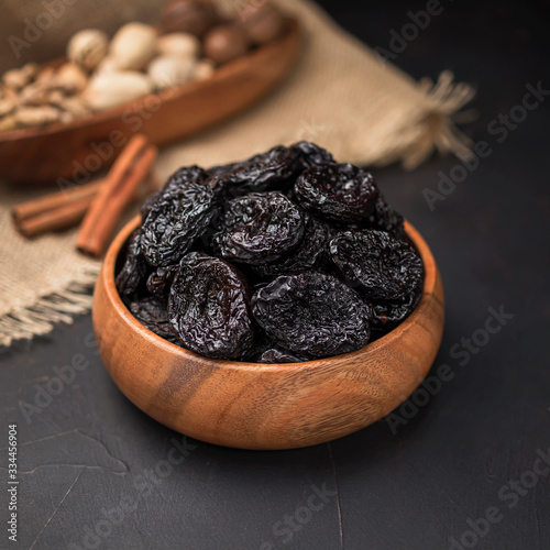 dried fruit in a square wooden bowl on a dark background and burlap