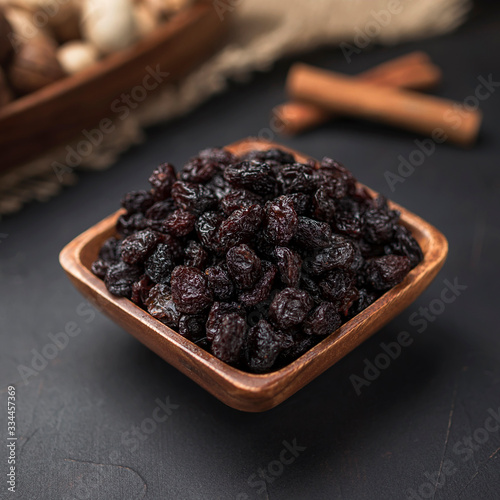 dried fruit in a square wooden bowl on a dark background and burlap