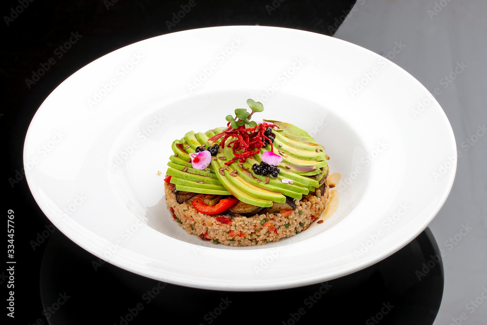 Salad with quinoa, avocado and roasted vegetables. On a colored wooden background. Vegetarian dish. Salad with quinoa, avocado and roasted vegetables. On a colored wooden background. Vegetarian dish.